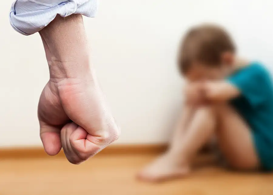 possible domestic abuse - blurred focus on fearful child in background, with man's fist looming in the foreground - champaign il